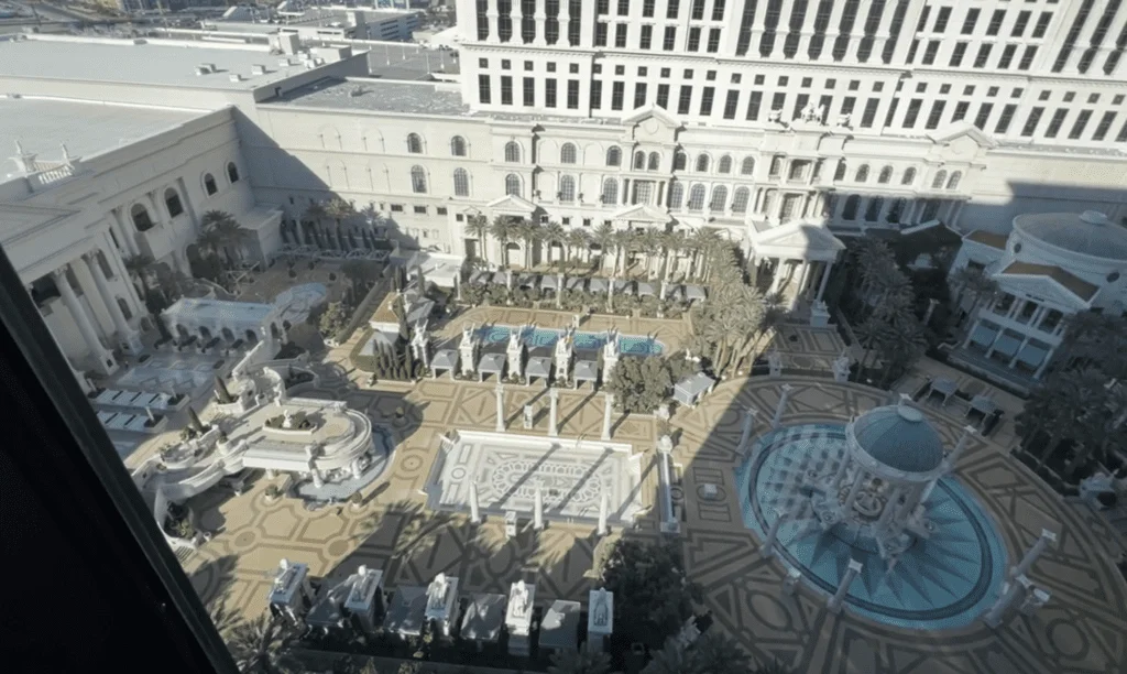 What It’s Like Staying at Caesars Palace Las Vegas - Still Cool? 24 Aerial view of Caesars Palace's expansive pool complex, with multiple pools and lounging areas, as seen from a 16th-floor room.